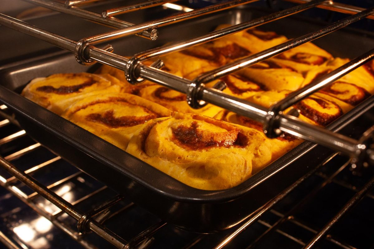 Pumpkin cinnamon rolls bake in the oven, ready to be frosted with cream cheese icing.