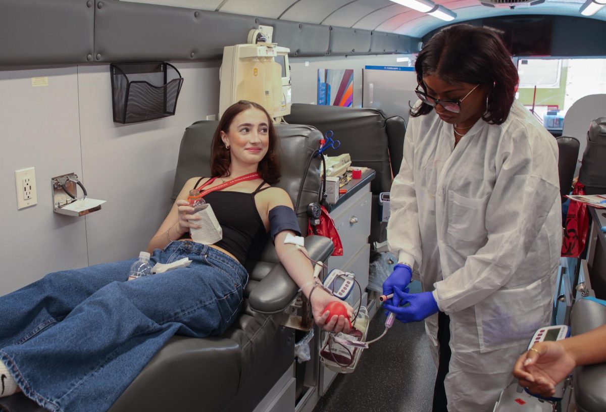 Looking at the phlebotomist, dance junior Finleigh Townsend gets blood drawn for her first time. On Oct. 16, National Honor Society (NHS) held its blood drive in the school parking lot. Oneblood Donation and its Big Red Bus visited the school campus to find volunteers for blood and plasma donations. Their mission is to replenish and maintain a healthy blood supply in the community. “It makes you feel really good to have had an impact on so many people by doing something that didn't take much time and didn't hurt me at all,” said Townsend.
