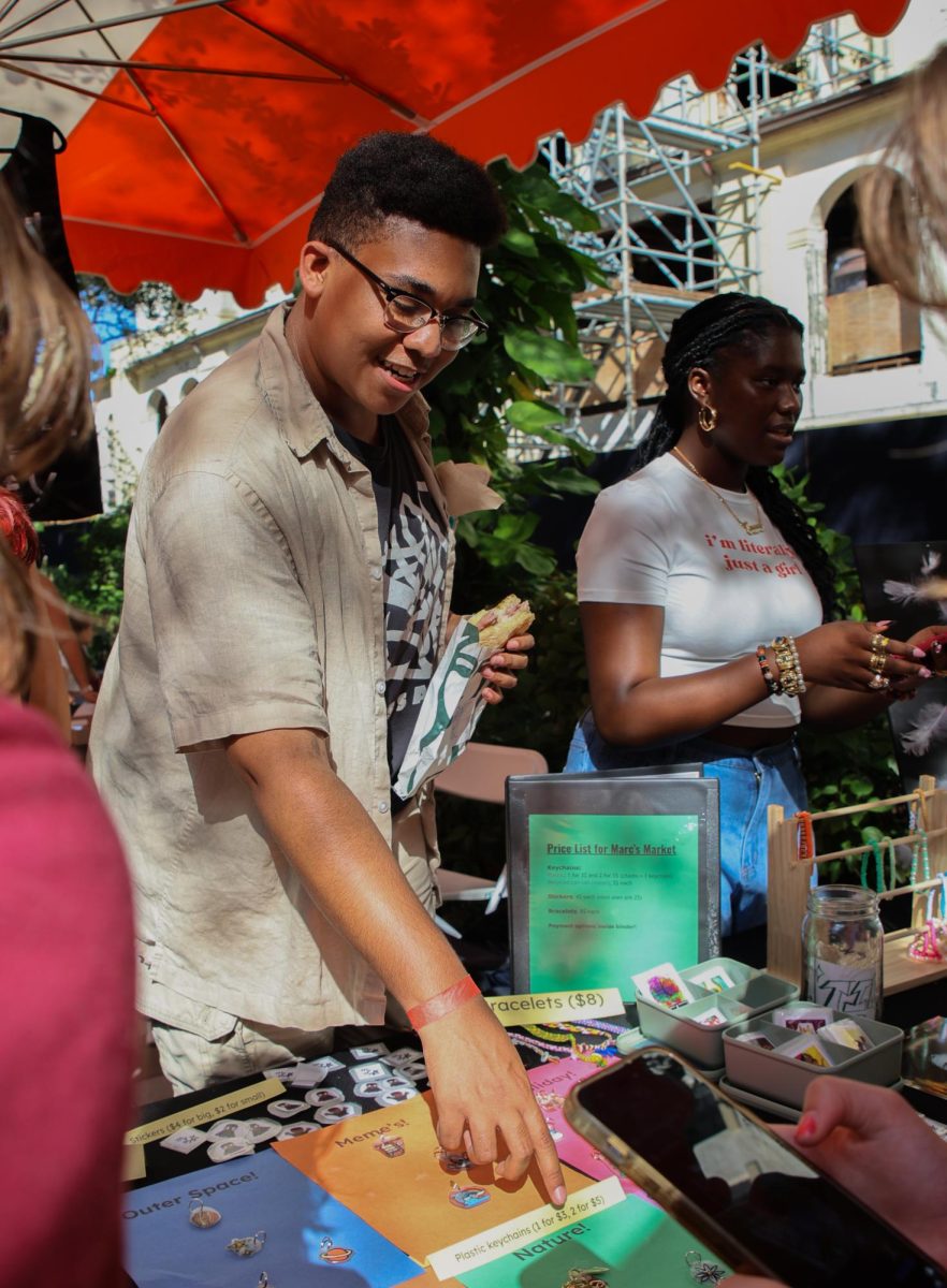 Presenting his artwork, visual sophomore Marcalix Lemene pitches his products to customers. “The Artist Market was a great experience. It was my first time this year, and I was very nervous that people were gonna be very competitive, but everyone was so sweet and generous,” Lemene said. “Next year, I will definitely be doing it again, and I’m very excited to see what my classmates, upperclassmen, and underclassmen will come up with next year!”