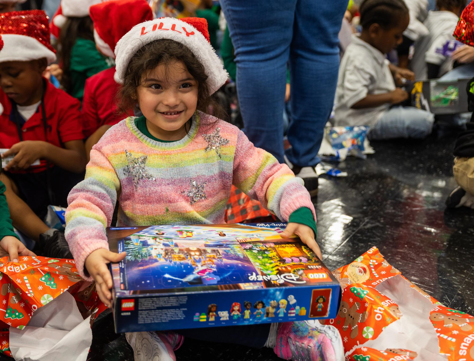 Sporting a Santa hat given to her by the ARTS Club, a little girl finishes unwrapping her present during the Jefferson Jubilee. Before the event, members of ARTS Club were assigned to buy toys and clothes for one child. The gifts the children received spanned from Lego sets to Barbie dolls and toy cars.
