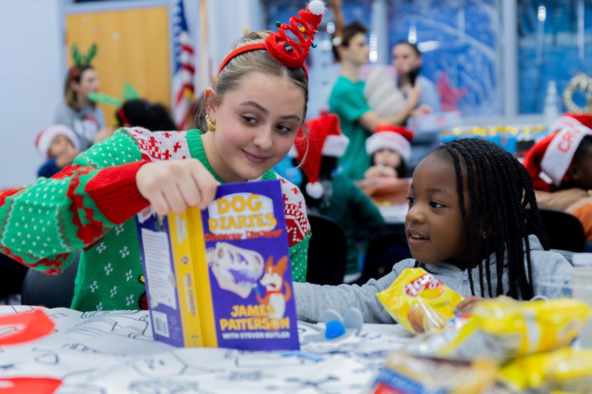 Reading out loud, dance junior Jillian Homeier holds up a book to assist a preschooler. Books were just one of the gifts that all children received; other gifts, including clothes, toys, and games, were taken home by the children. The ARTS Club manages this Jefferson Jubilee event off of school and community involvement by asking ARTS Club members to donate Christmas gifts and buy clothes for their assigned kid.
