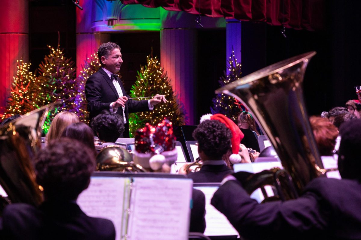 Band director Evan Rogovin prepares the symphonic band for the piece “C’est Noel” as the curtains rise behind him. This piece was the fourth of the night and spanned over three minutes and 40 seconds. 