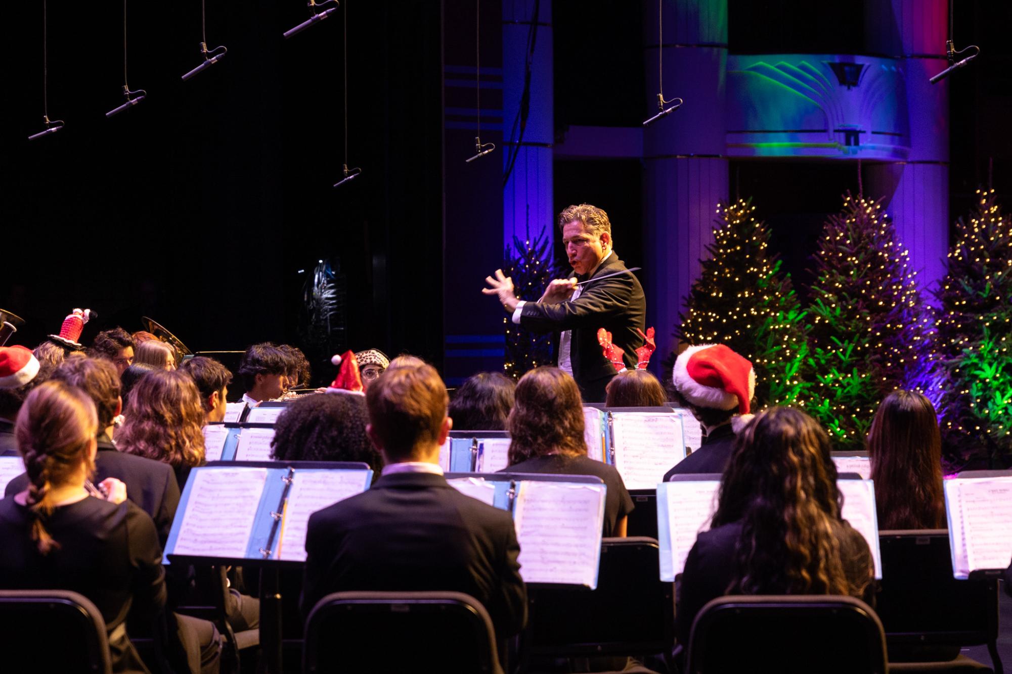 Band director Evan Rogovin swiftly moves his arms as he conducts a piece. This piece was the fourth composition of the night, titled “C’est Noel,” which was performed by the symphonic orchestra.