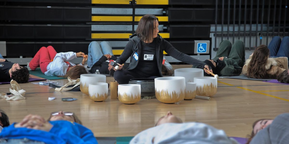 Tracing around glass singing bowls, a volunteer for the second annual Mental Health Expo attempts to calm the students lying on yoga mats surrounding her.  