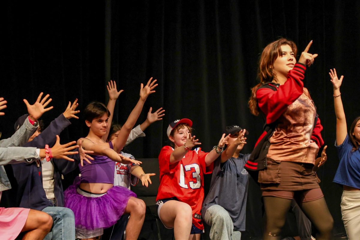 Pointing out to the audience, theatre senior Katherine Oliver executes the song “Gaston” with the rest of the actors during the Broadway Backwards show. Broadway Backwards was performed in the Black Box Theater during lunch on Jan. 31 where female actors performed as male characters and vice versa during presentations of Broadway plays and musicals. The actors had to audition to get into the performance and were from all grade levels.