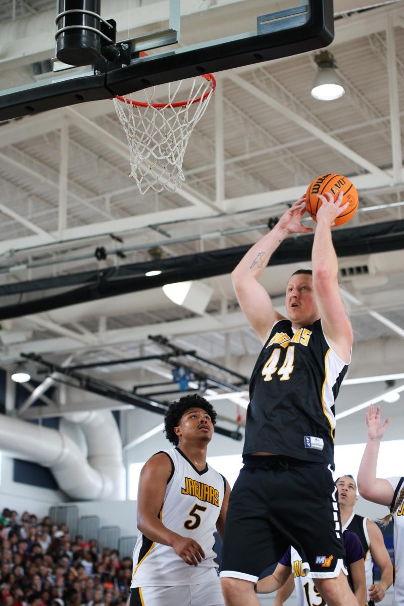 Jumping toward the net, girl's basketball coach and math teacher Joshua Millstein attempts to dunk the ball.