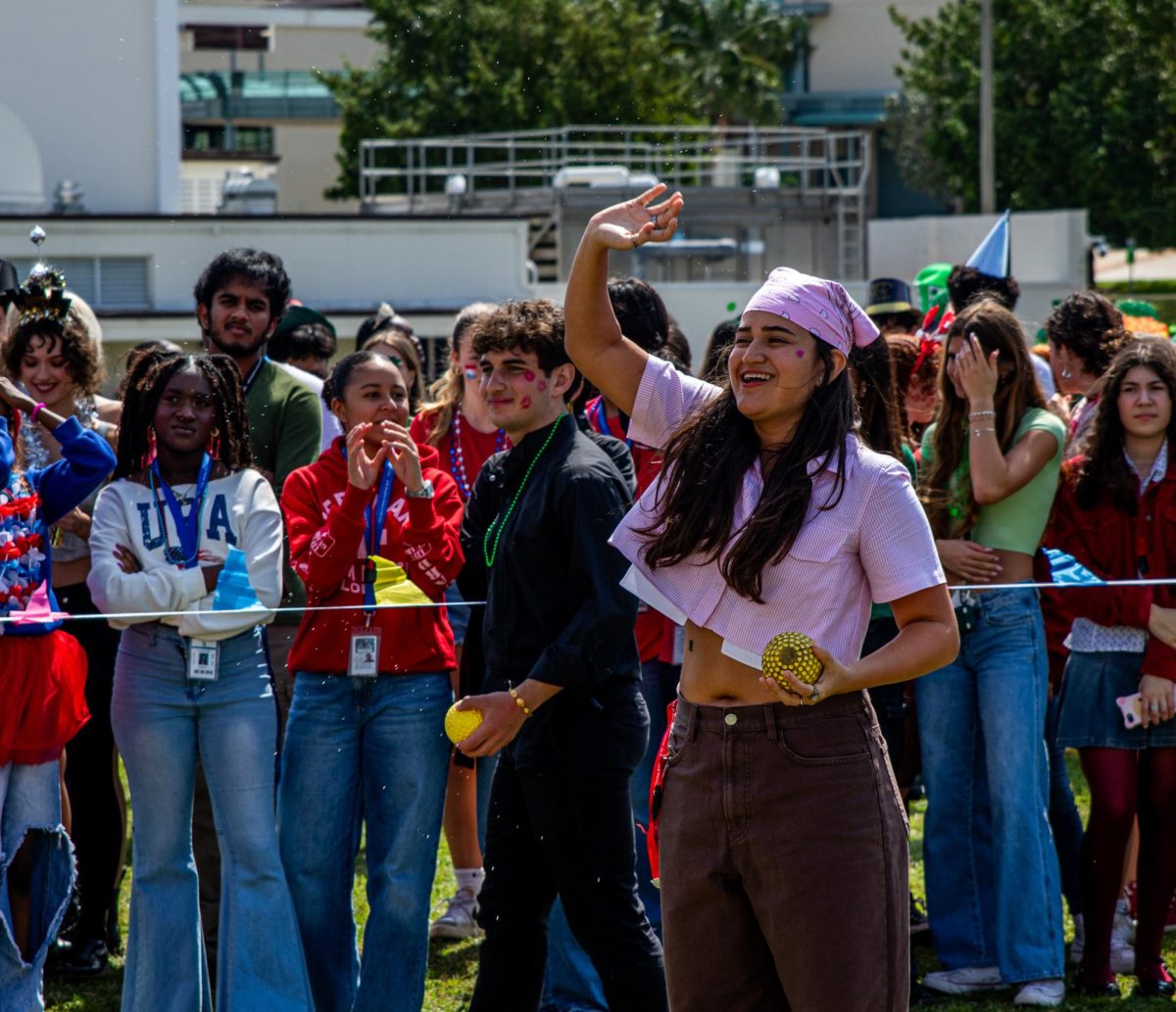 Waving her hand, digital media junior Camila Obando prepares to throw a ball to dunk math teacher Craig Adams. Adams was one of 7 teachers that got dunked during field day. 