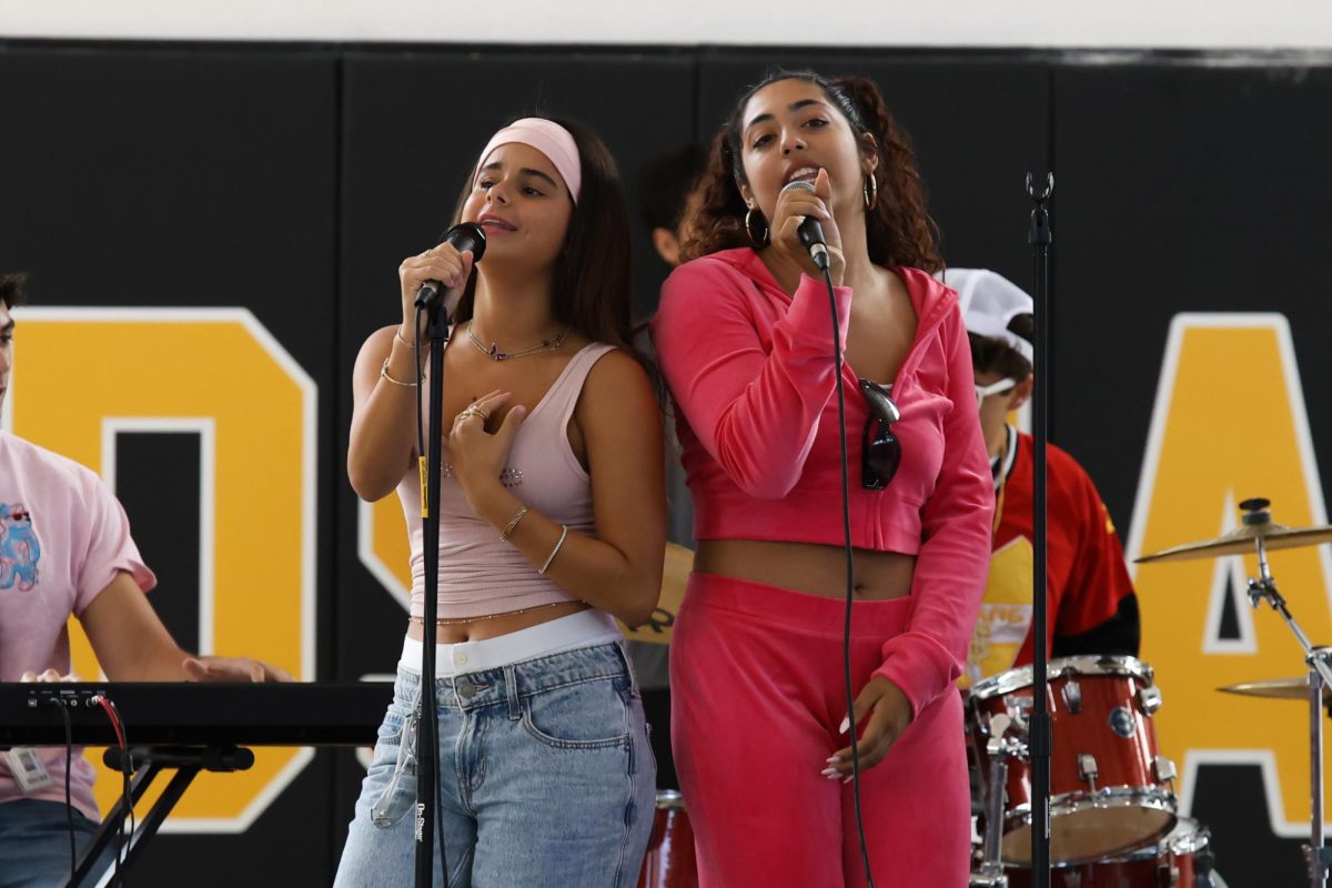 Performing for the senior class in Battle of the Bands, an event hosted during lunch on Tuesday of Spirit Week, communications senior Emma Yela Bueno and vocal senior Giuliana Siqueira sing a medley of songs which fall into the Y2K music genre. 